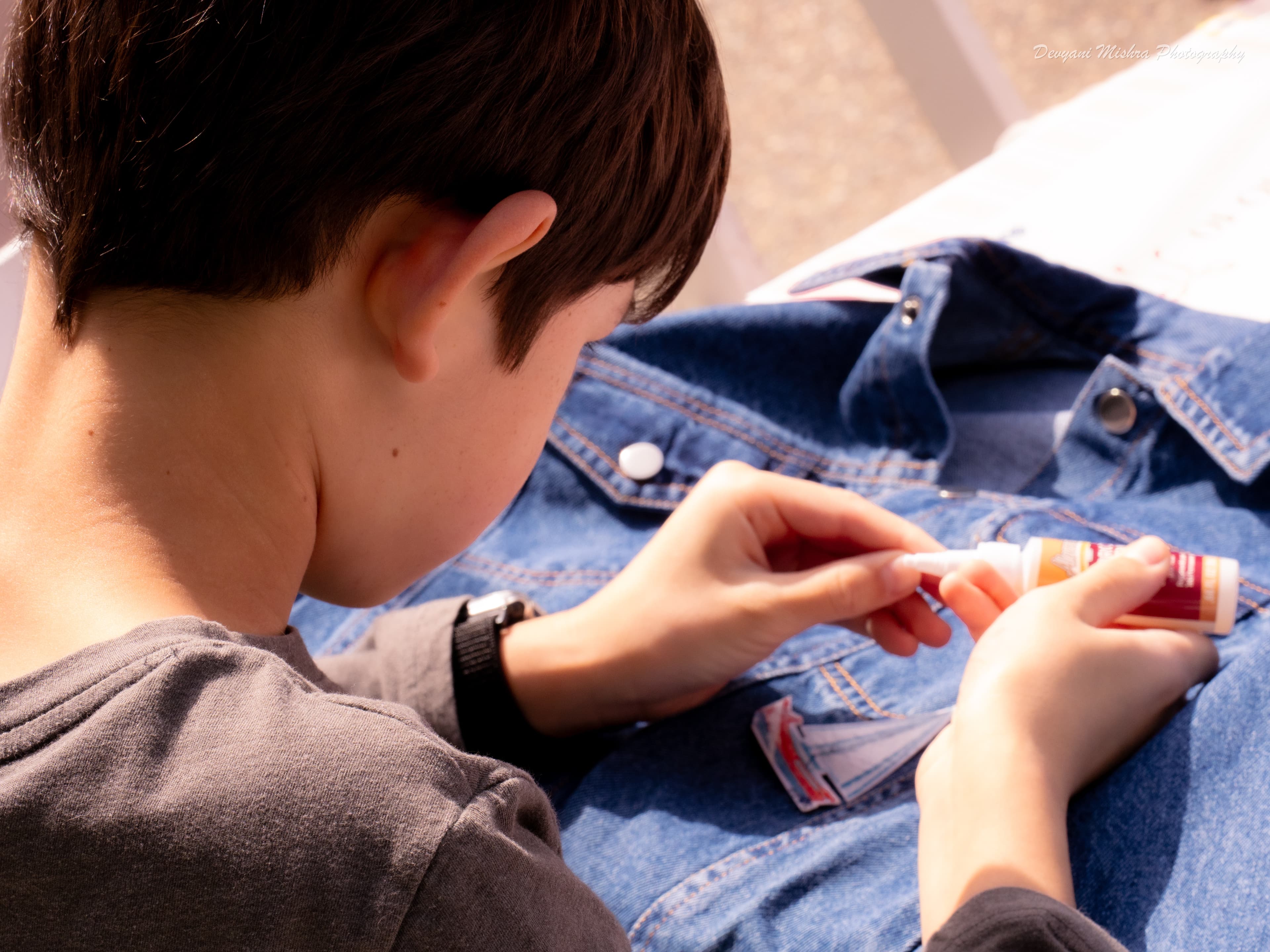 Over-the-shoulder close-up of a kid applying a patch to their denim jacket — Jacket Studio
