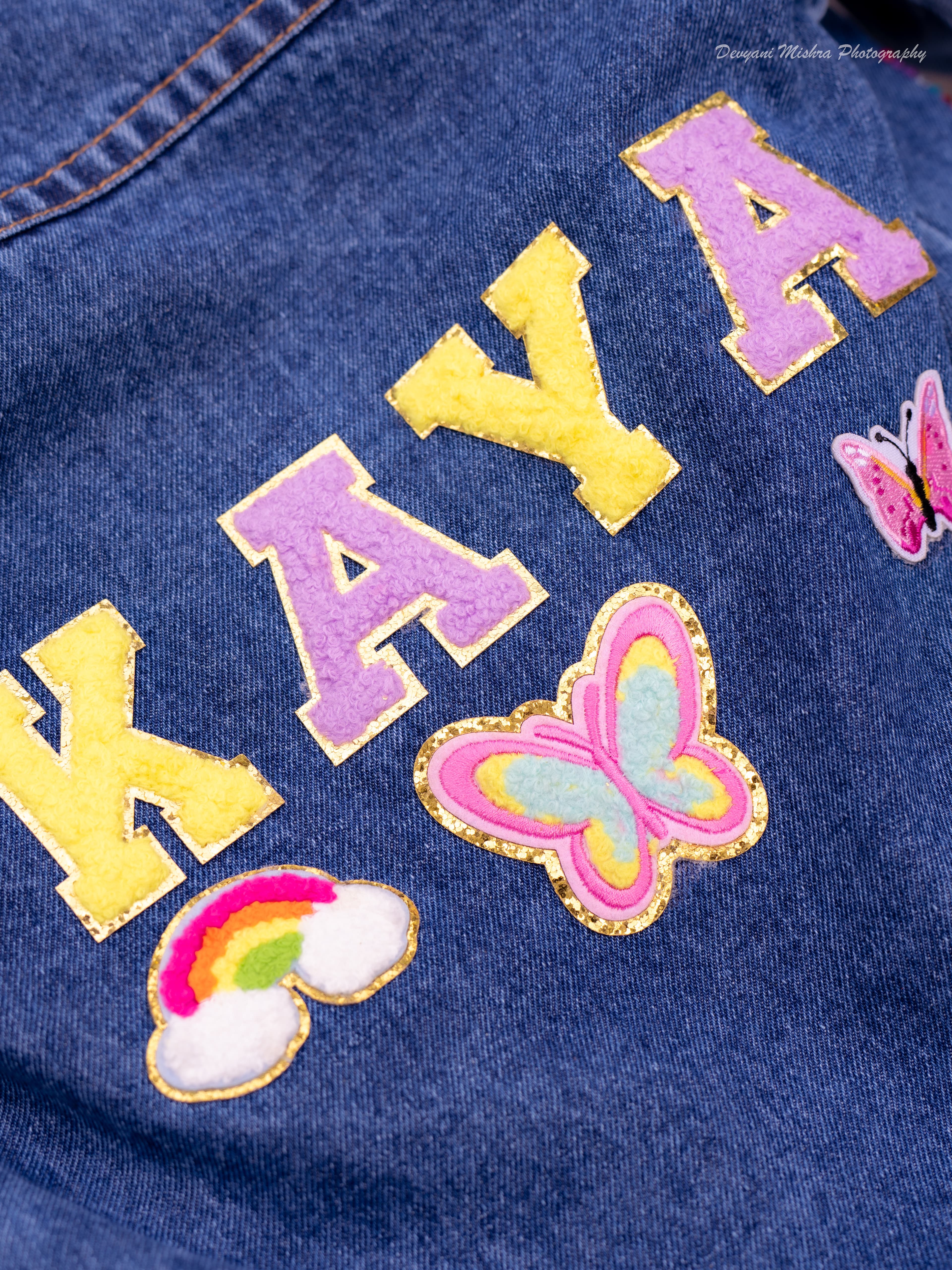Finished denim jacket spelling KAYA in chunky chenille letter patches — guest designed and made