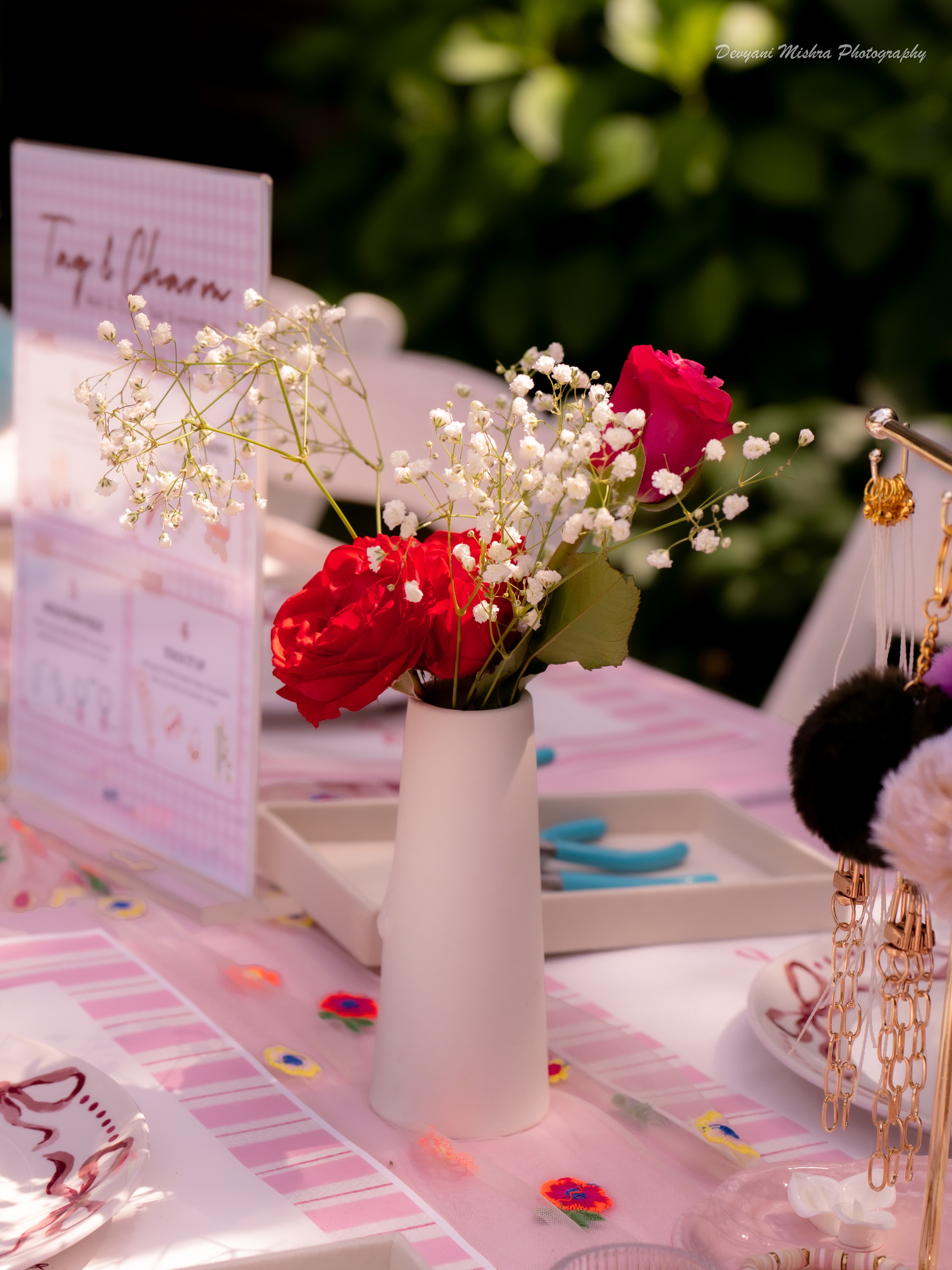 Tag & Charm table setup — activity sign, fresh flowers, gold jewelry display