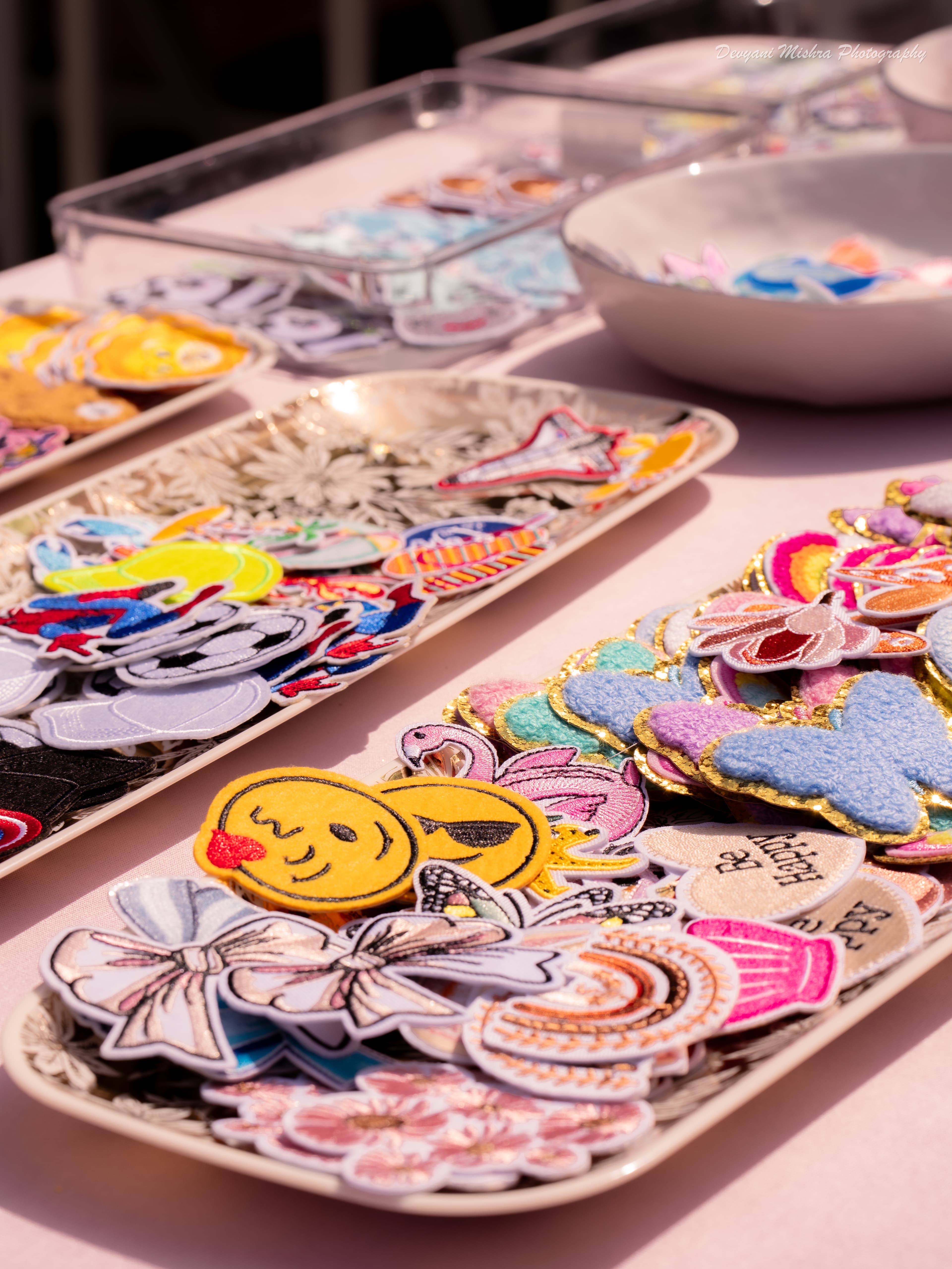 Embroidered and chenille patches on platters — bows, butterflies, smiley faces, letters