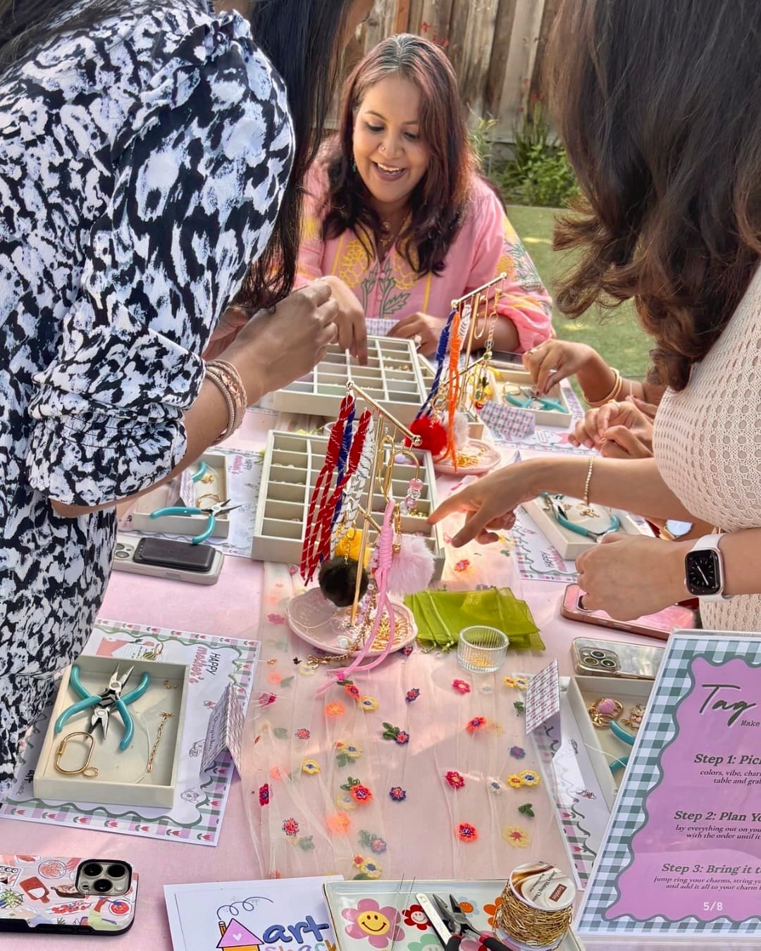 Women laughing together around the jewelry-making table